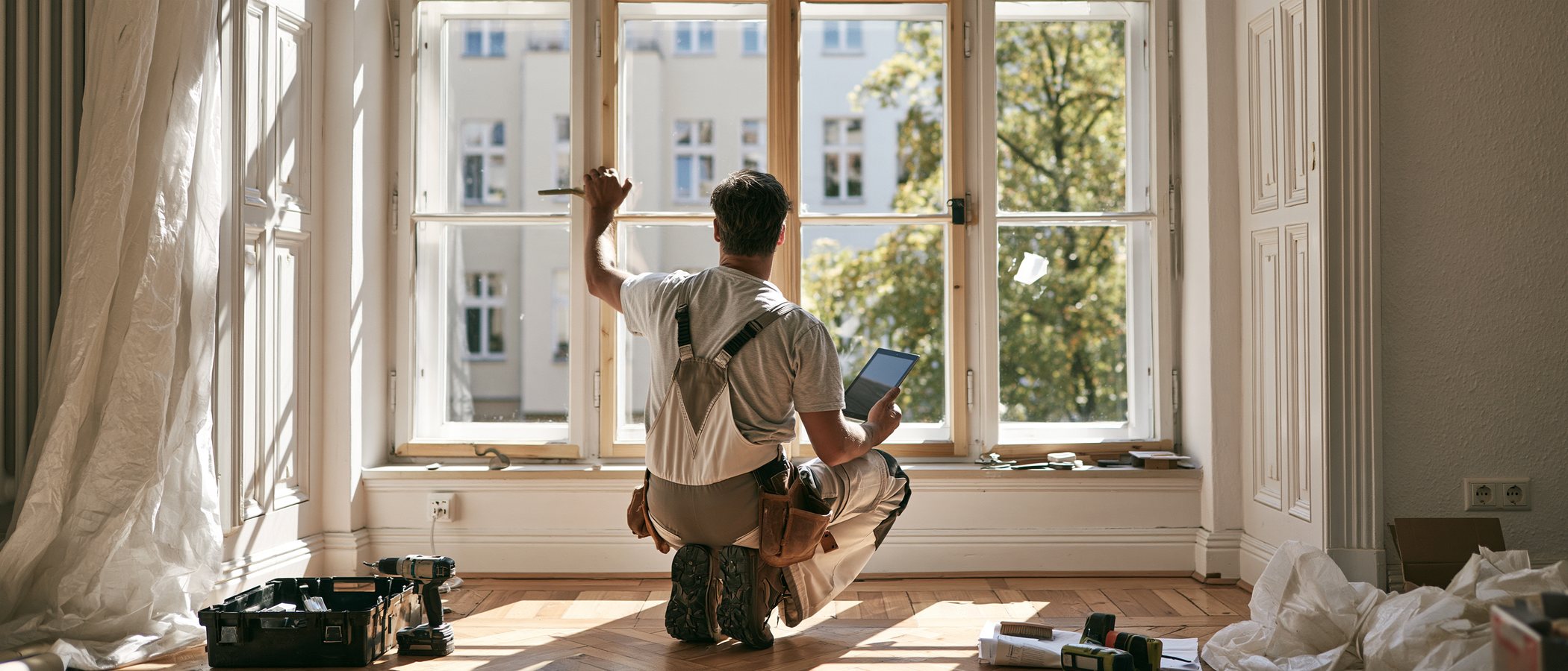 Fensterbauer mit Tablet vor einer Fensterfront in einer Wohnung